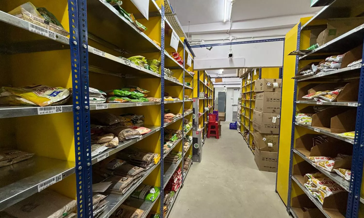 The general groceries section of the dark store, each shelf has a sticker with a unique code and barcode ID, indicating the specific products on the shelf and their location